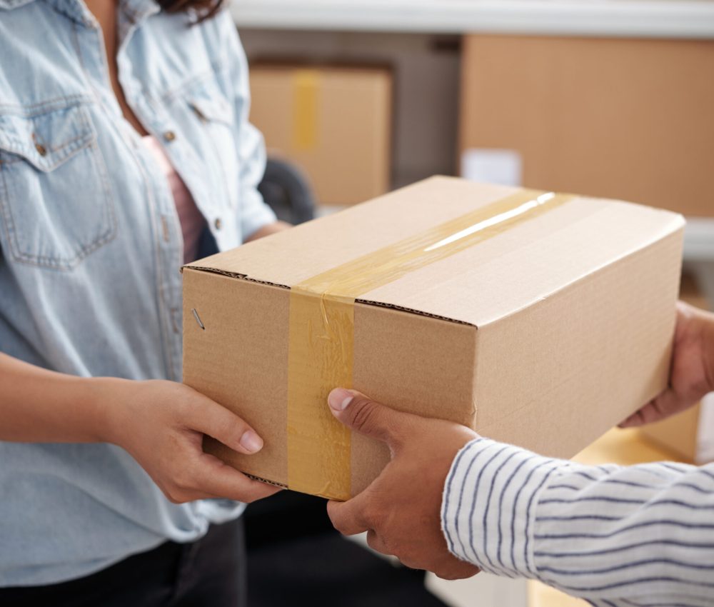 Close-up of woman receiving cardboard box from delivery man